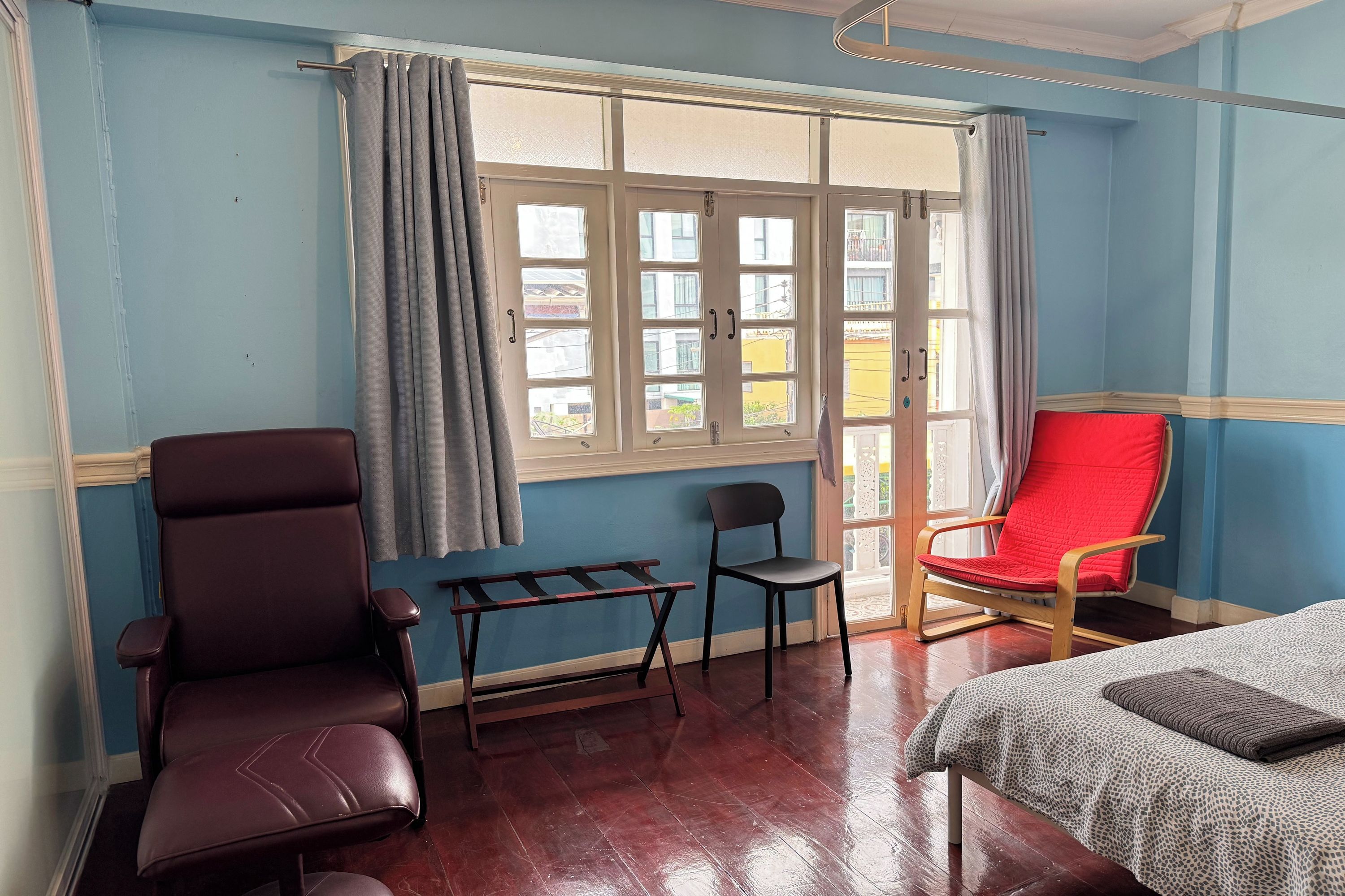 A room with a bed, two chairs, a small table, and a window with curtains.
