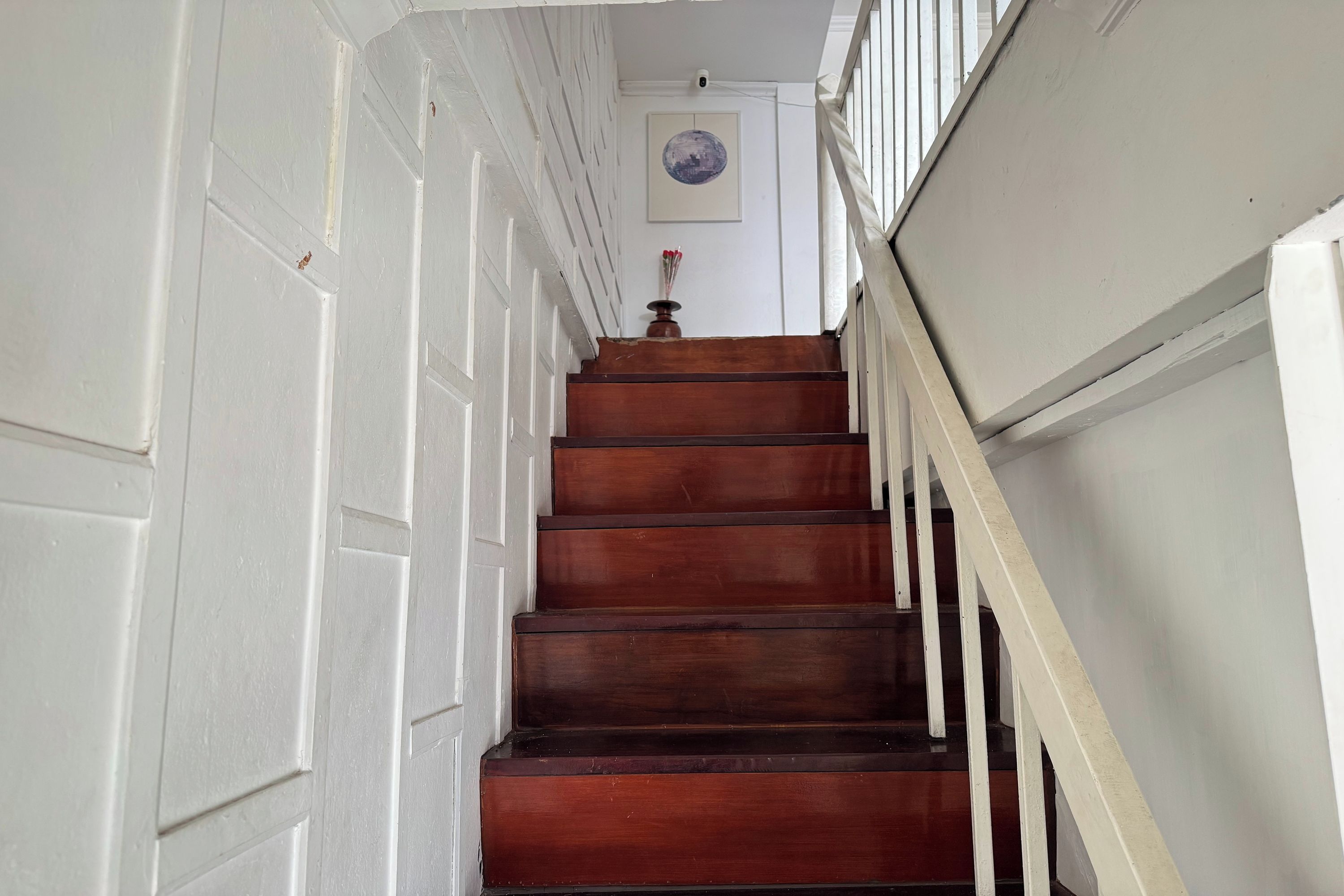 A wooden staircase with white walls and a door at the top.