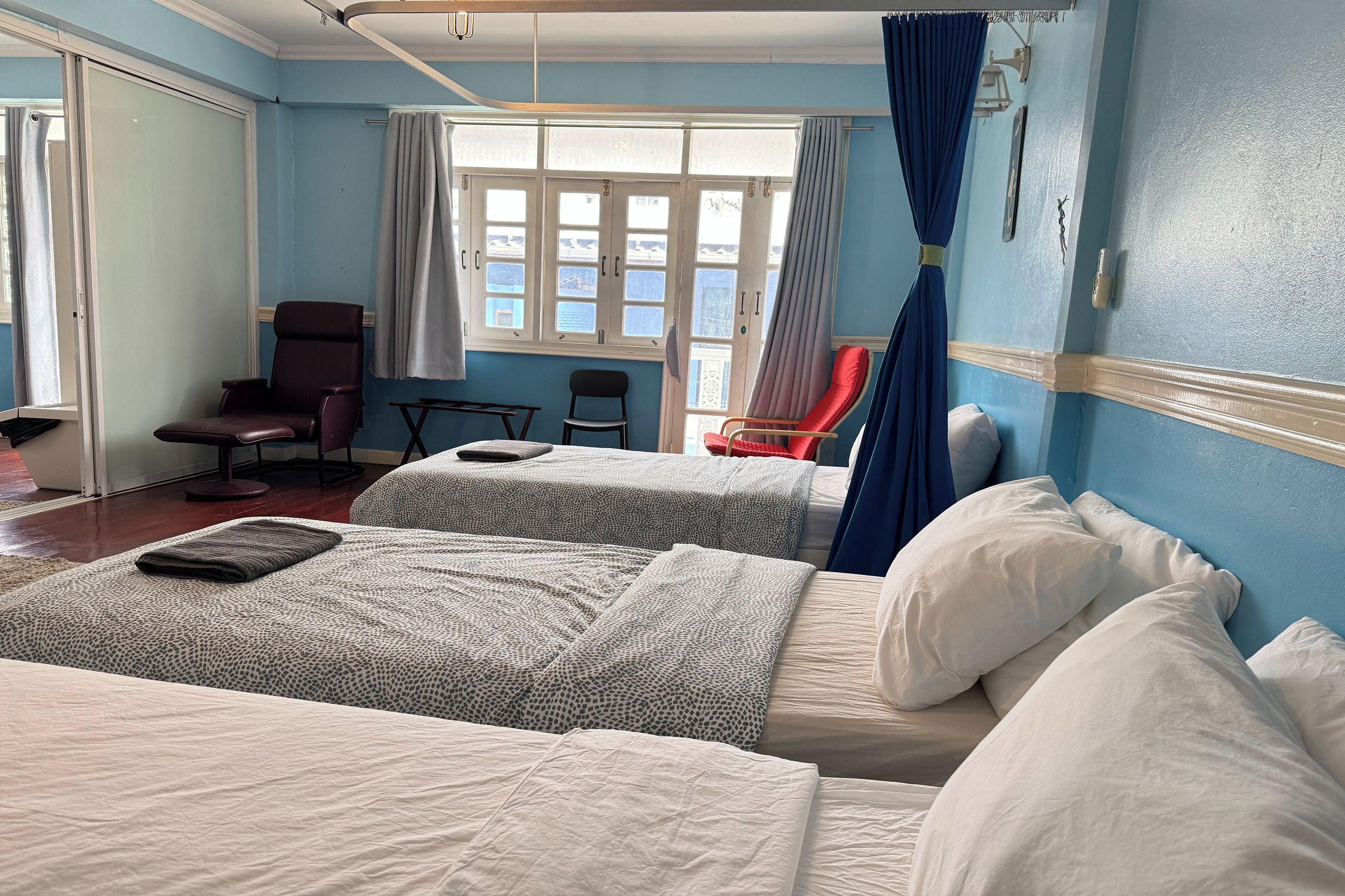 A hotel room with two beds, a desk, a chair, and a window with curtains.