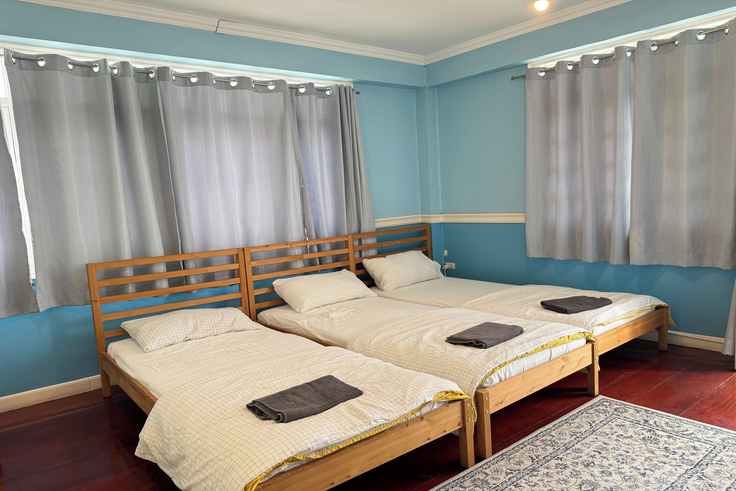 A room with two single beds, a wooden headboard, and a patterned rug.