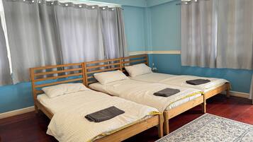 A room with two single beds, a wooden headboard, and a patterned rug.