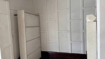 A hallway with a white door, a wall with rectangular panels, and a dark wooden baseboard.