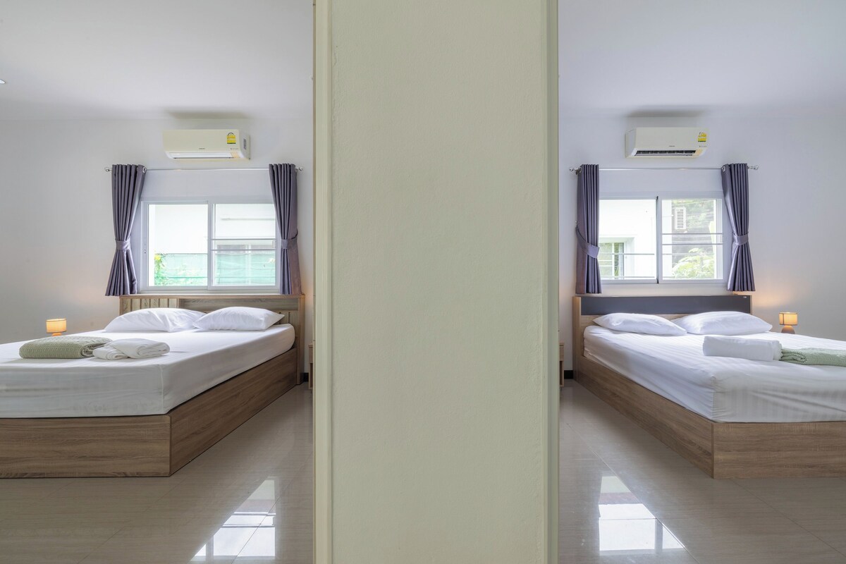 A mirrored room with two beds, each with a wooden headboard, white bedding, and a bedside lamp.