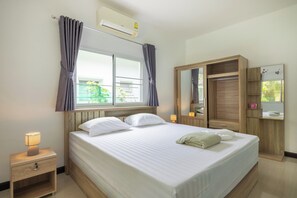 A hotel room with a bed, a nightstand, a wardrobe, a mirror, and a window with curtains. - Villa Ras Kamala (Kamala)