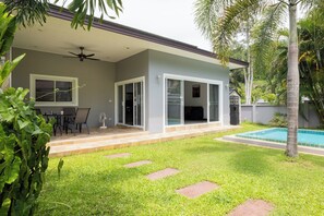 Una casa moderna amb un porxo cobert, una piscina i un jardí.