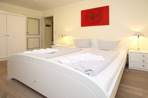 A bedroom with a double bed, two bedside tables, a red abstract painting, and a wardrobe. - Holiday apartment in Föhr with 2 bedrooms (Wyk auf Föhr)