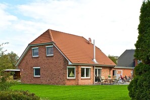 A two-story brick house with a sloped roof, a visible chimney, and a well-maintained lawn. - Holiday home in Tating with swimming pool (Tating)
