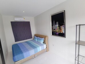 Ein Schlafzimmer mit einem Bett, einem Stadtlandschaftsposter, einem dunkel gefärbten Kopfteil und einem Metallregal.