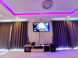 A modern living room with a flat-screen TV mounted on the wall, a sound system, and a decorative plant. - Fortune PoolVilla at Huahin (Tambon Hin Lek Fai)