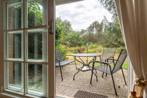An open door leading to an outdoor patio with a round table and four chairs. - Holiday apartment with 1 bedroom (St.Peter-Ording)