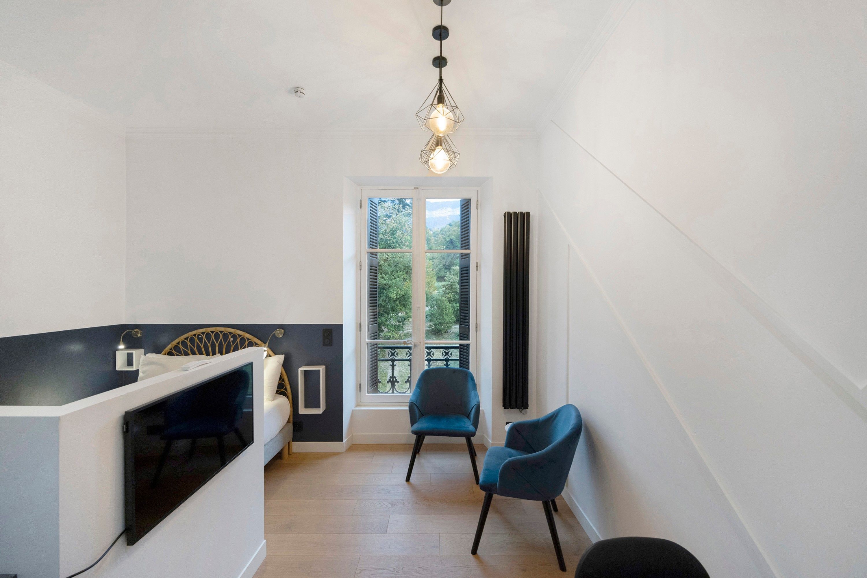 Una stanza compatta con un letto, un angolo salotto, una finestra vista e un termosifone.