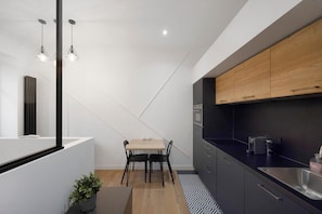Eine moderne Küche mit Essbereich, mit einem Holztisch, schwarzen Stühlen und einer schwarzen Arbeitsplatte mit Spüle.