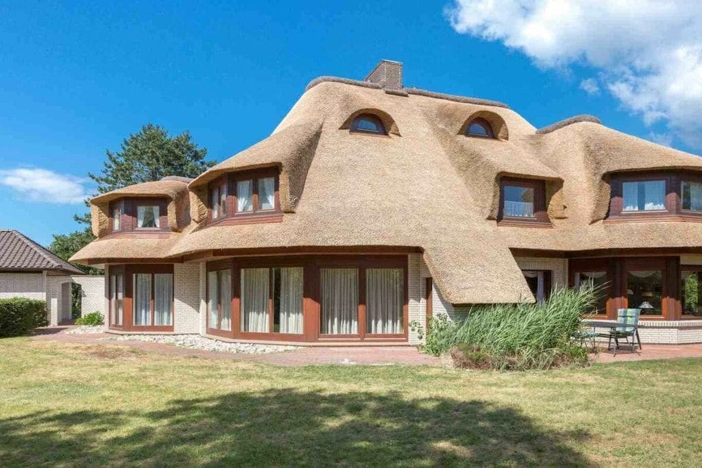 A house with a unique architectural style featuring rounded, earthen-colored roofs and large windows.