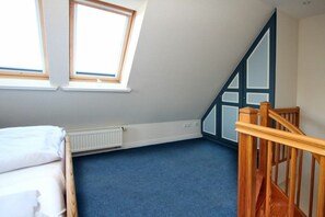 A room with a sloped ceiling, a radiator, a wooden staircase, and a bed. - Rungholtstraße 6a, Holiday Apartment 3 (Wyk auf Föhr)