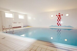 An indoor swimming pool with a tiled floor, a ladder, and a wall with a red and white abstract design. - But Dörp 3, Holiday Apartment 3 (Wyk auf Föhr)