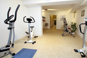 A home gym with stationary bikes and a treadmill, carpeted floor, and a door leading to another room. - But Dörp 3, Holiday Apartment 3 (Wyk auf Föhr)
