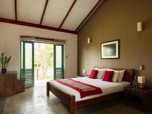 A bedroom with a wooden bed, a red throw, and a view through a door to the outside. - Hide Yala Lakeside Hideaway - 2 Bedroom Nature Retreat with Pool (Kataragama)