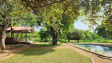 A pool area with a gazebo, trees, and a well-maintained lawn.