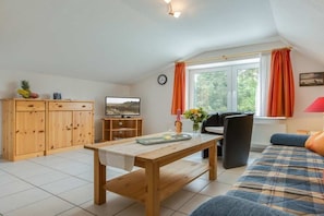 A cozy living room with a wooden table, a sofa, and a television. - 5 in the house Sturmmöwe (ID 117) (St. Peter-Ording)