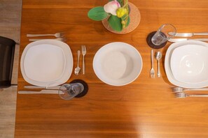 A wooden dining table with four white plates, cutlery, and a glass of water. - 6 in the Pole Poppenspäler house (ID 211) (St. Peter-Ording)