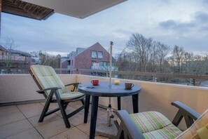 A balcony with two chairs and a small table, a brick building in the background, and a clear sky. - 6 in the Pole Poppenspäler house (ID 211) (St. Peter-Ording)
