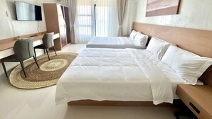 Ein Hotelzimmer mit Bett, Schreibtisch, Stuhl, Fernseher und einem großen Fenster mit Vorhängen.