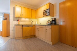 Eine Küche mit Holzausstattung, einer Mikrowelle und einer Kaffeemaschine.