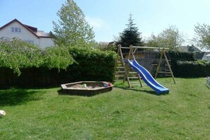Ein Garten mit einer Holzwentil und einer blauen Rutsche.