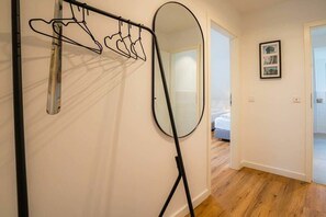 A room with a mirror, a clothes drying rack, and a bed in the background. - 10 in the Nis Randers house (ID 291) (St. Peter-Ording)