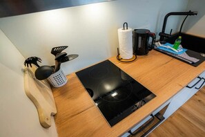 A kitchen with a black induction cooktop, a kettle, a coffee maker, and a kettle holder. - 10 in the Nis Randers house (ID 291) (St. Peter-Ording)