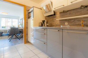 A modern kitchen with a built-in oven, a coffee maker, and a wooden backsplash. - Holiday apartment with 2 bedrooms (St. Peter-Ording)