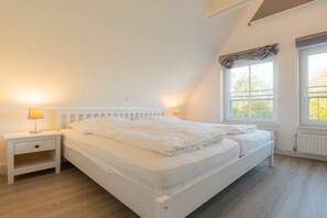 A bedroom with a bed, nightstands, and a window. - Dat Lütte Huus (ID 424) (Tümlauer Koog)