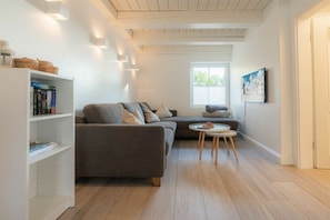 A modern living room with a grey sofa, a small round table, and a bookshelf. - Dat Lütte Huus (ID 424) (Tümlauer Koog)
