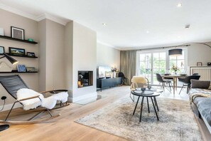 A modern living room with a fireplace, a dining area, and a sofa. - Holiday home Captain Karl Keitum / Sylt (Nordfriesland)