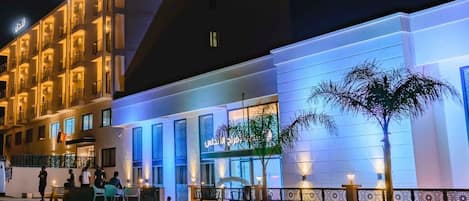Un hotel con piscina, zona de estar al aire libre y fachada bien iluminada.