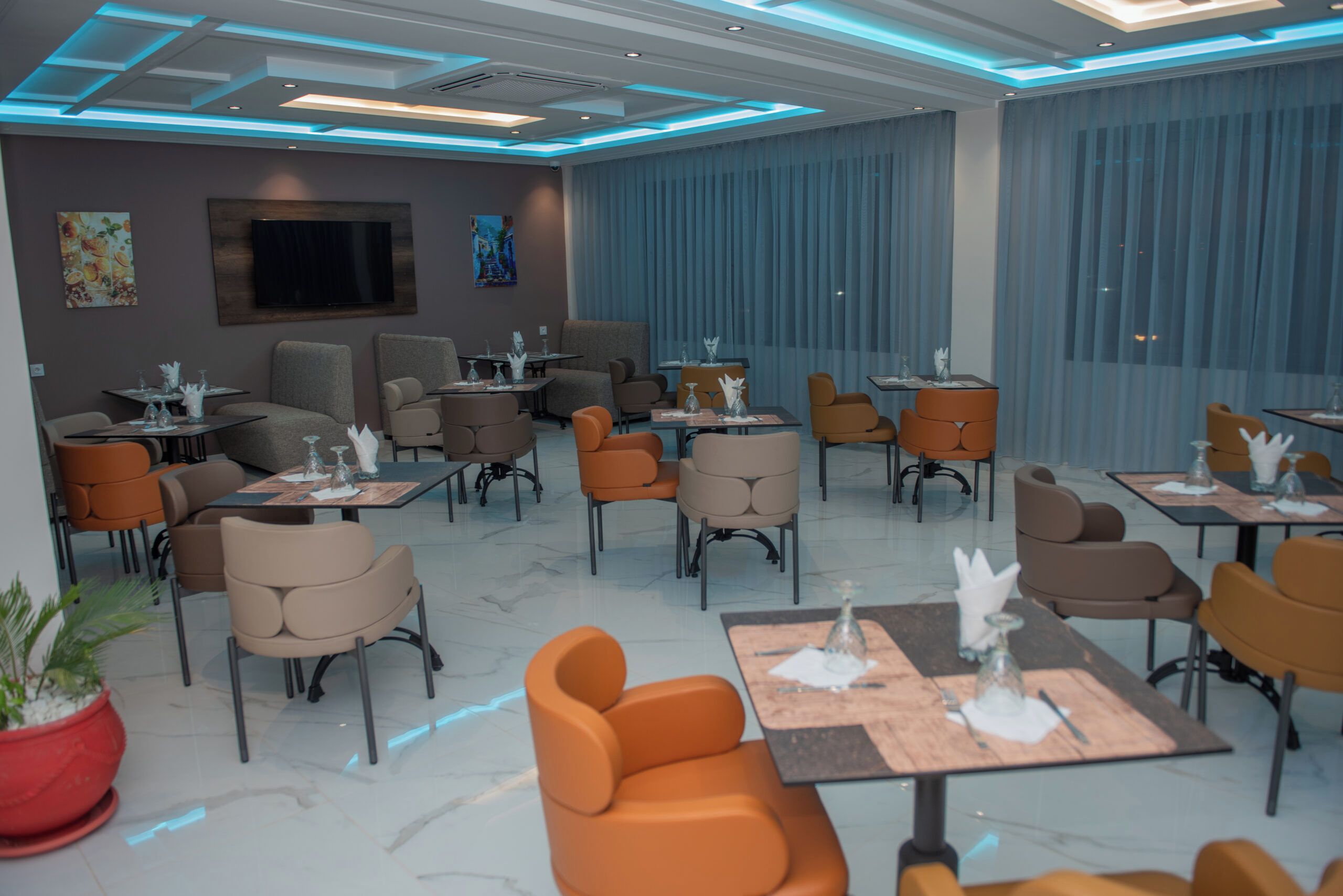 A modern restaurant with a variety of seating options, including tables and chairs, and a large window with curtains.