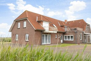 A two-story brick house with a sloped roof, large windows, and a visible balcony. - OG in the Everschop house (ID 135) (St. Peter-Ording)