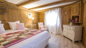 A wooden room with a bed, a chair, a dresser, and a window with curtains. - LA GRANGE AUX COQS (Ittenheim)