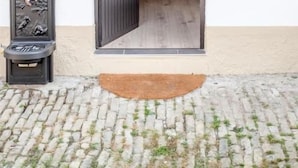 A doorway leading to a room with a wooden interior, a small table with a lamp, and a wall-mounted light fixture. - LA GRANGE AUX COQS (Ittenheim)