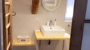 Een badkamer met een plafond van houten balken, een wit wastafelmeubel, een spiegel en een raam.