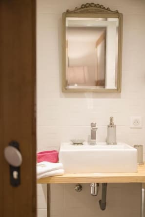Une salle de bain avec un lavabo blanc, un miroir et un porte-serviettes.