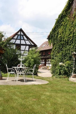 A traditional building with a steeply pitched roof, surrounded by lush greenery.