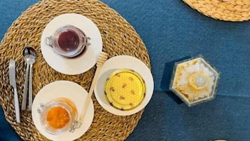 Un tavolo apparecchiato con piatti, bicchieri e posate su sottopiatti di vimini.