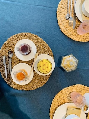Une table dressée avec des assiettes, des verres et des couverts, le tout posé sur des sets de table en fibres tressées.
