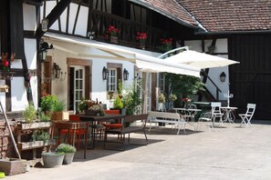 An outdoor seating area with tables and chairs, surrounded by potted plants and flowers.