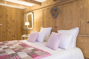 Une pièce aux murs lambrissés, avec un lit, une table de chevet, une lampe et un décor en forme de cœur accroché au mur.
