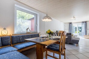 Ein Essbereich mit einem Holztisch, blauen Sitzbänken mit Polsterung und einer hängenden Leuchte.
