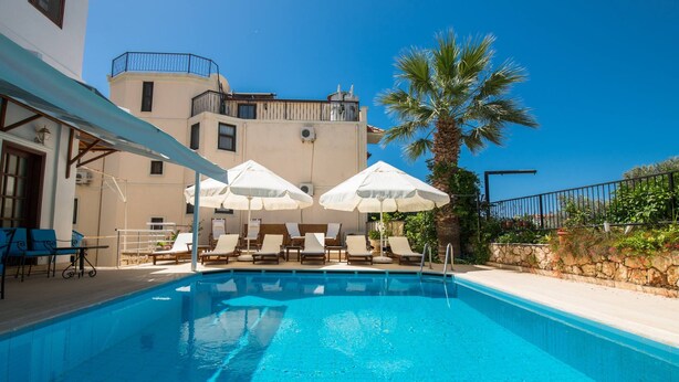Ein Pool mit Liegestühlen und Sonnenschirmen, umgeben von einem Gebäude mit einem Balkon.
