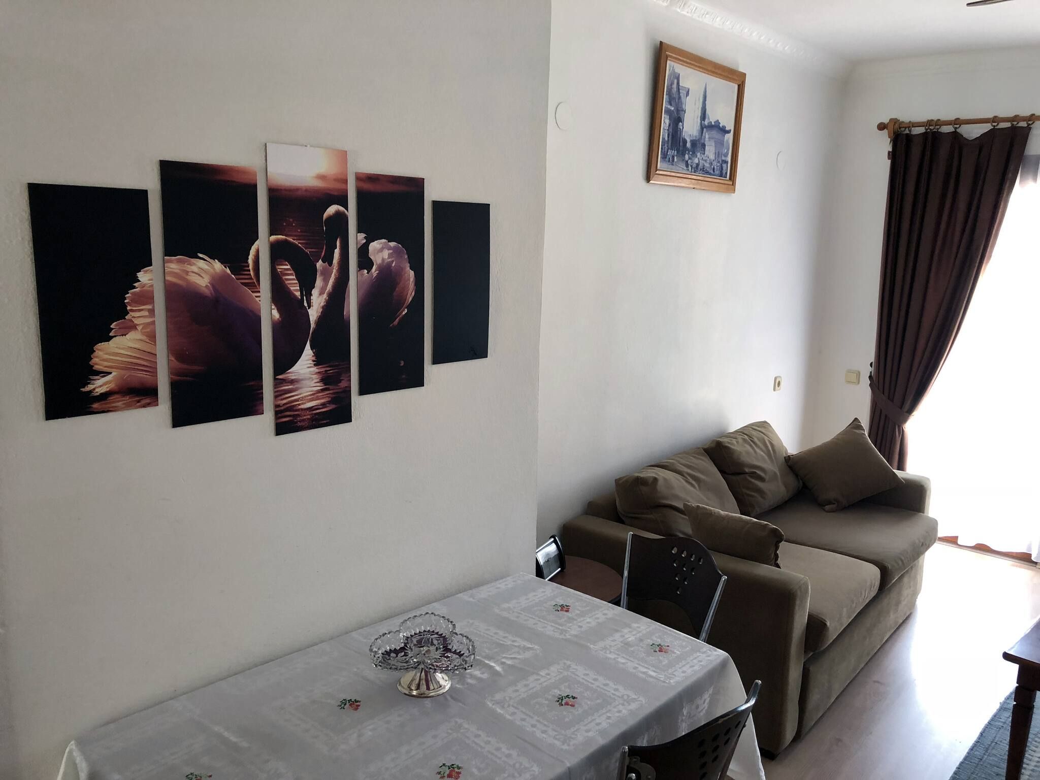 Un salon comprenant un canapé, une table à manger agrémentée d’un centre de table en verre et des œuvres d’art murales.