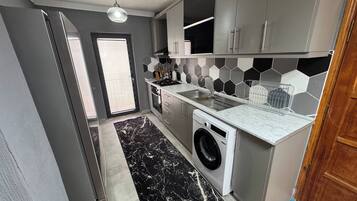 Une cuisine moderne avec des meubles gris, un lave-linge et un dosseret de crédence en carreaux hexagonaux.
